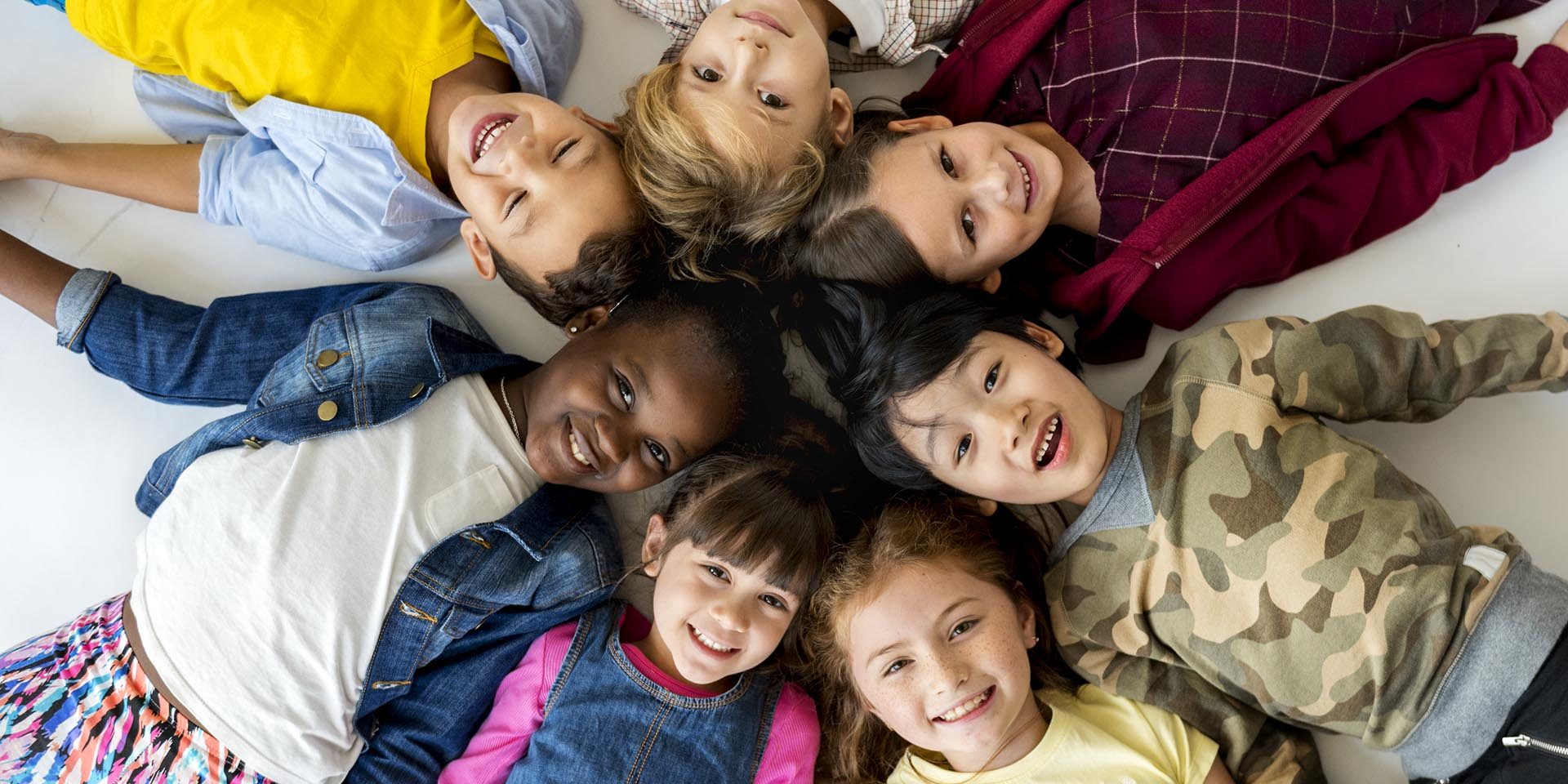 A group of primary schoolers lying on the ground and smiling